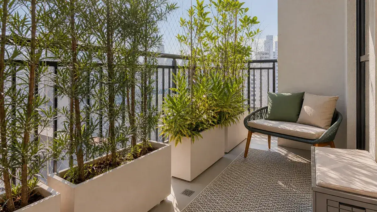 Plantas altas em jardineiras internas criando privacidade em varanda pequena de apartamento.